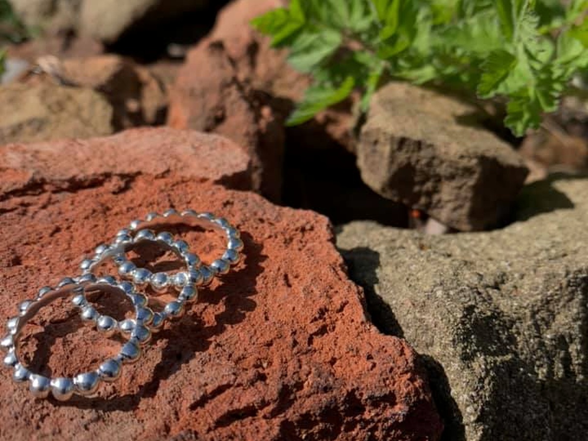 Circular beaded silver pieces photographed on stone